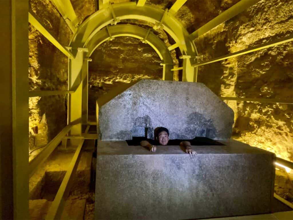 Man standing inside a massive stone box in the Serapeum.
