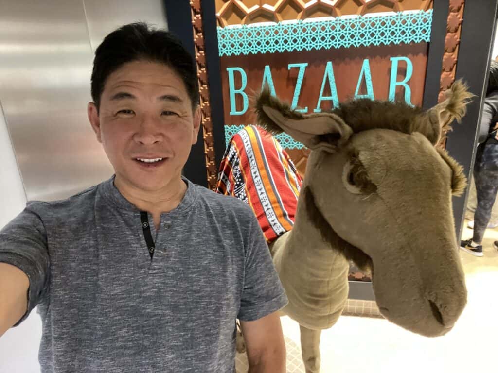Man standing next to a large stuffed camel