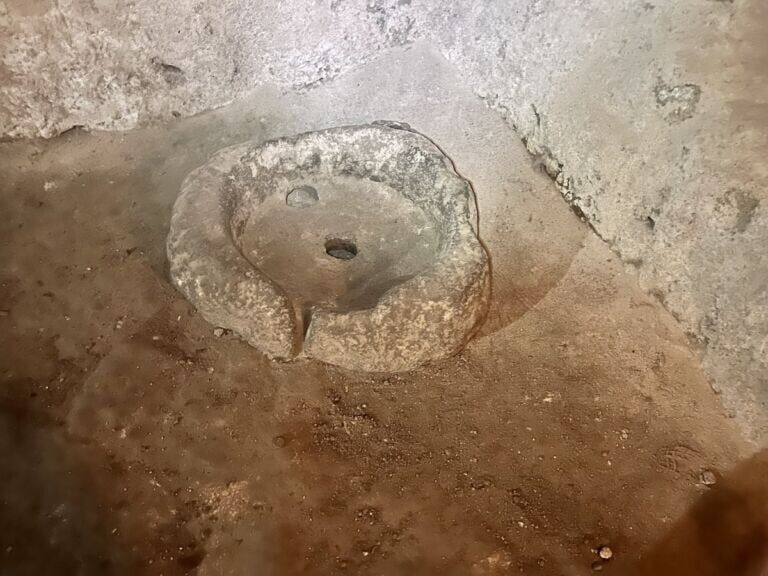 Raised ring of stone with a slot in the edge and hole in the center.