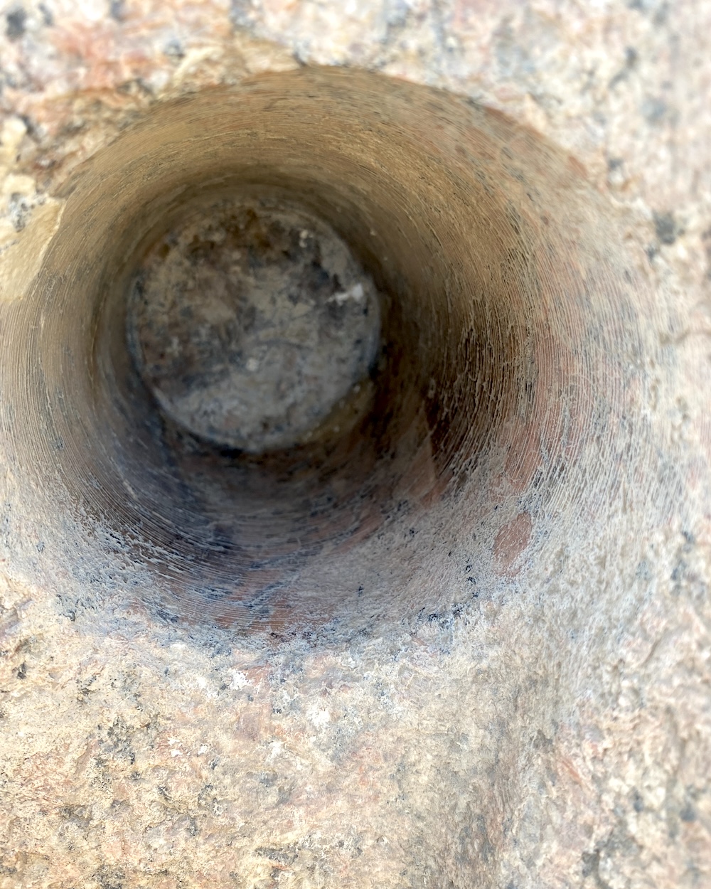 Close-up of a precision cylindrical core drill hole carved into granite at the Sun Temple of Niuserre at Abu Ghurab in Egypt showing concentric drilling marks inside the stone surface