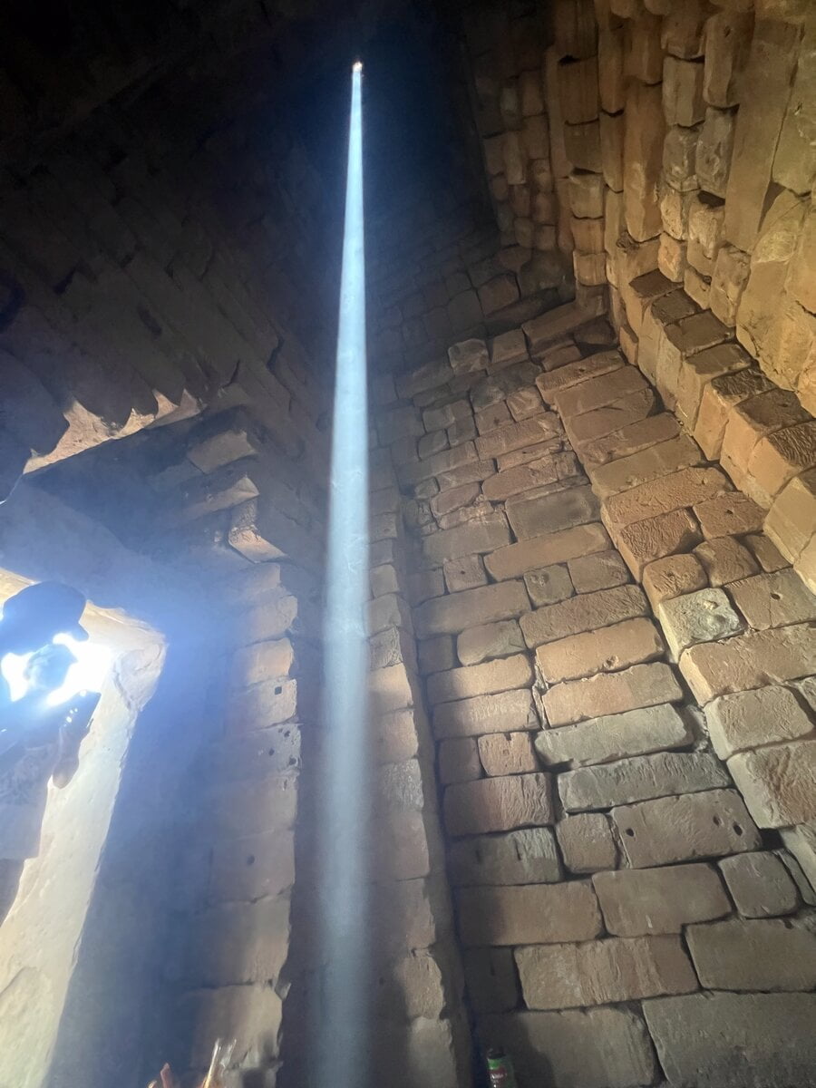 Sunlight beam entering through roof opening inside the central tower of Bakong temple during the zenith sun alignment in Cambodia