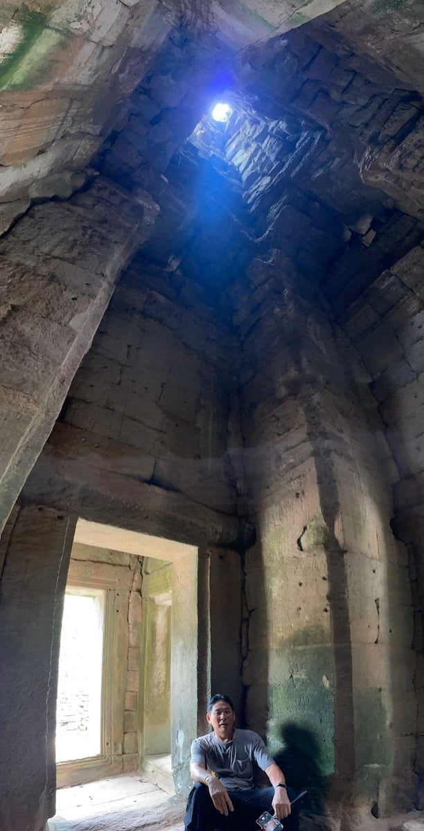 Vertical beam of sunlight entering through the upper opening of the Bakong temple sanctuary tower in Cambodia illuminating the massive stone interior during the zenith sun event
