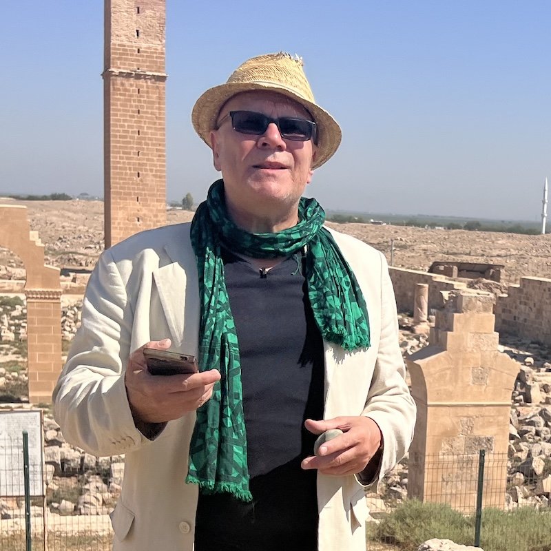 Author Andrew Collins in a hat and green scarf at an ancient site in Turkey