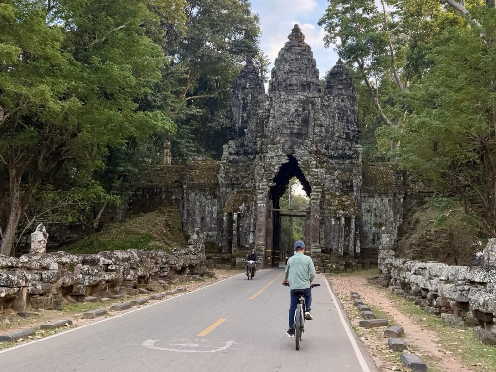 Guide Kanha Phum cycling along the causeway toward the face-tower North Gate of Angkor Thom