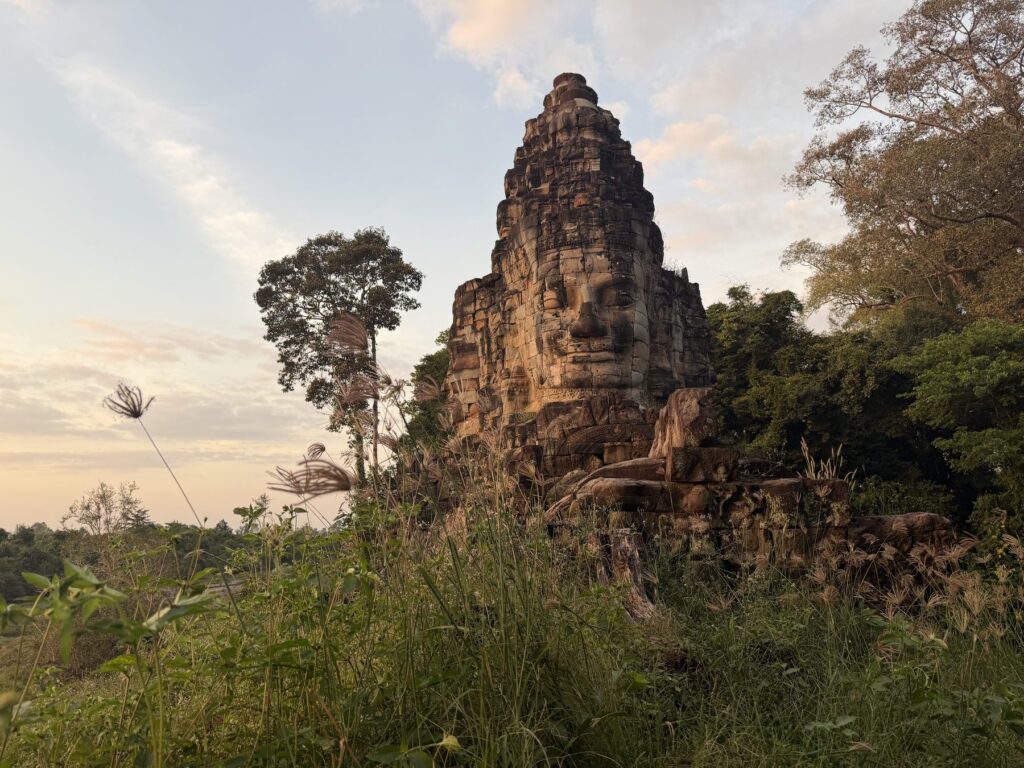 A carved face on the West Gate tower of Angkor Thom glowing in the last sunlight