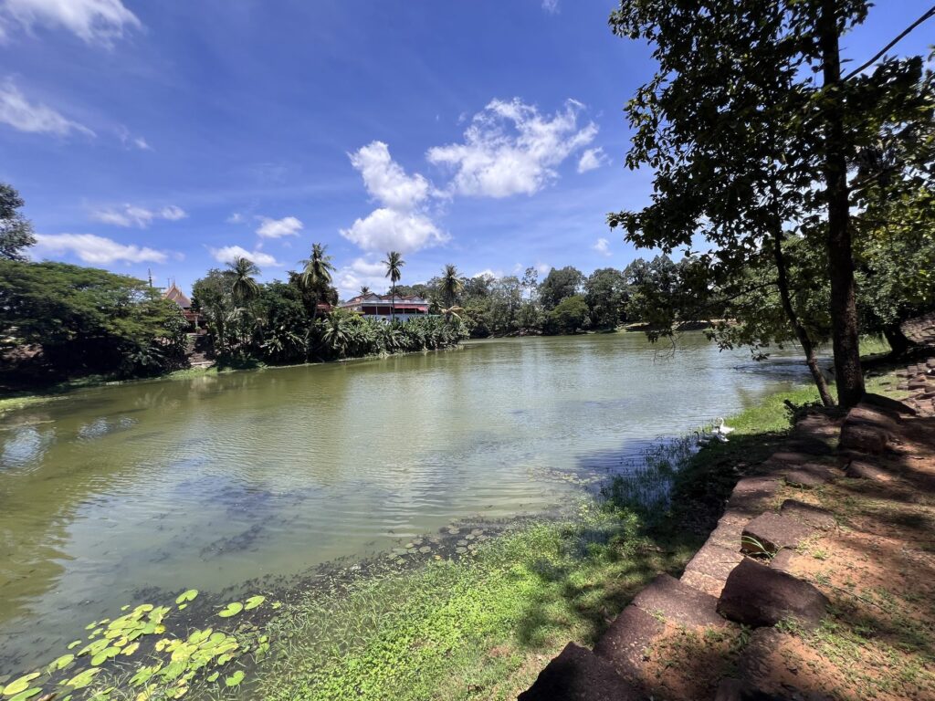 The wide moat around Bakong temple with trees and lily pads along the bank