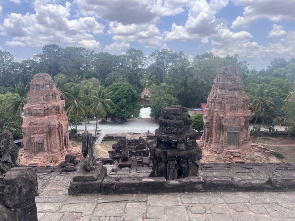 Brick satellite towers and a stone tower seen from the upper level of Bakong temple