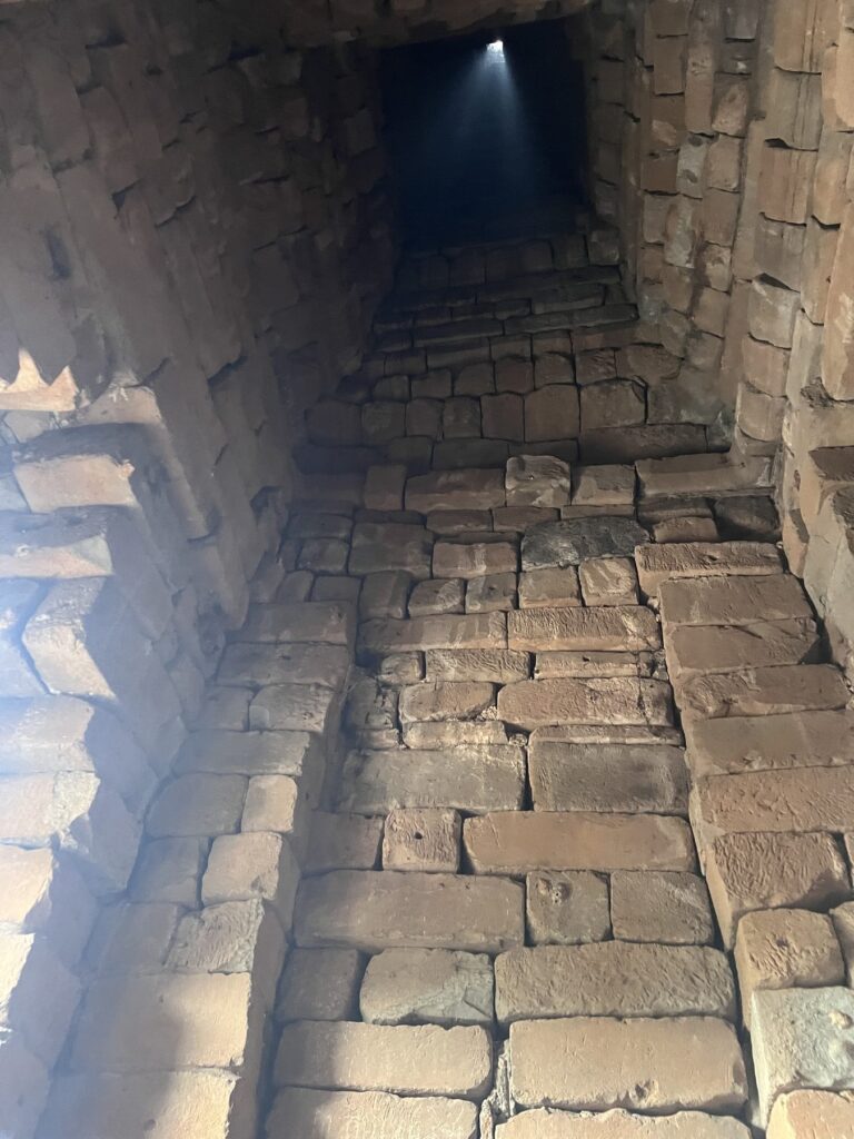 The sunbeam inside Bakong's central tower in April, already angled a few minutes after solar noon