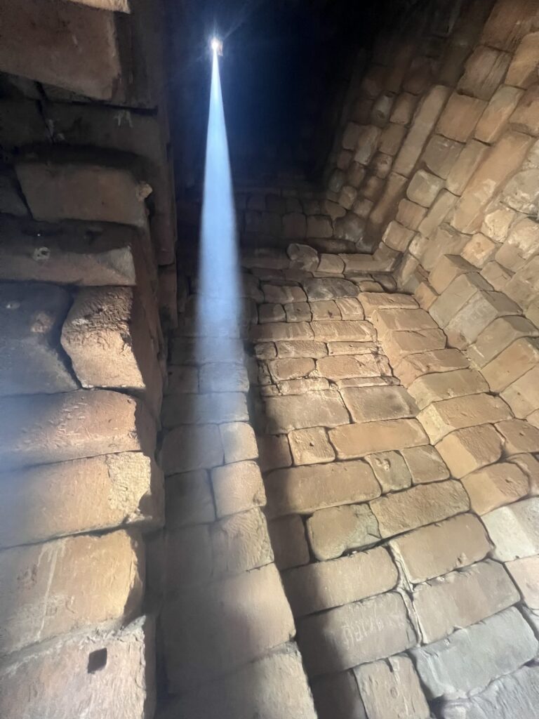Twenty minutes after the zenith, the sunbeam inside Bakong's tower slanting onto the stone wall