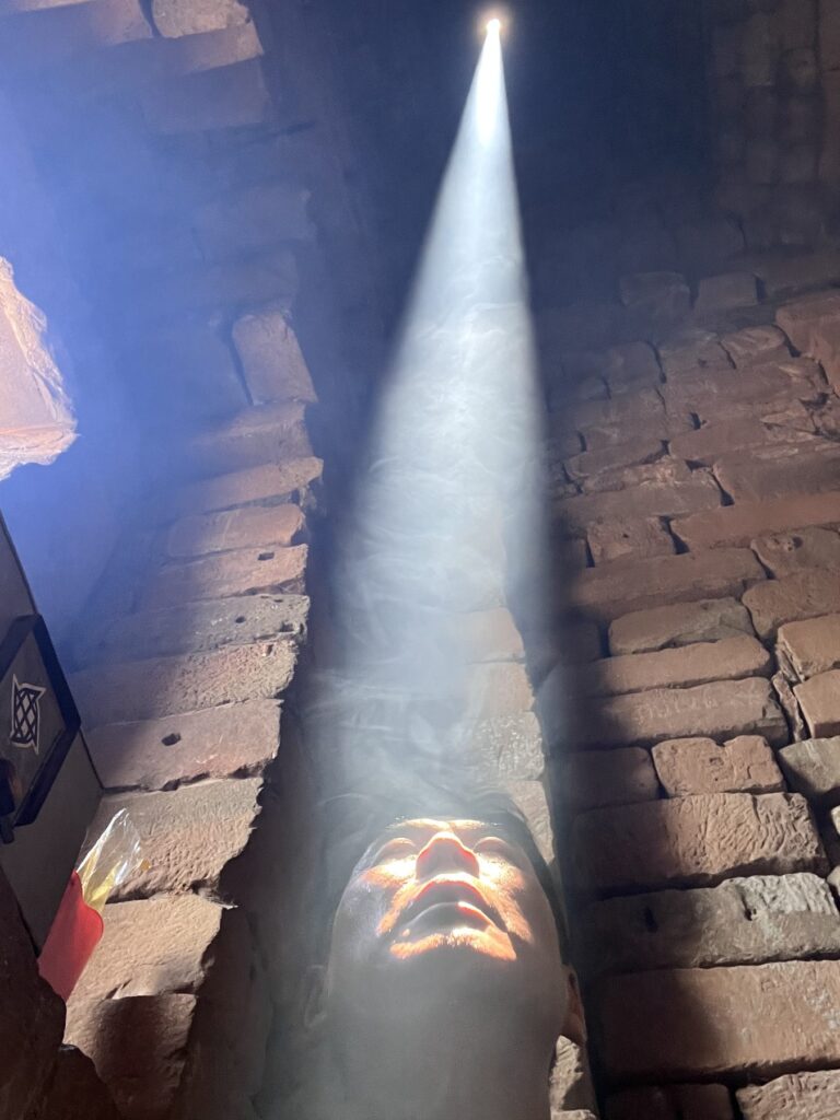 The author looking up into the zenith sunbeam inside Bakong's central tower, light on his face