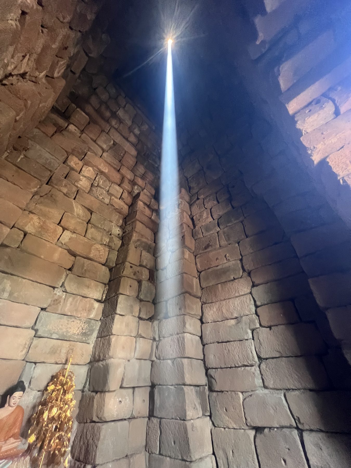 A vertical beam of sunlight dropping from the roof opening of Bakong's central tower at the August zenith