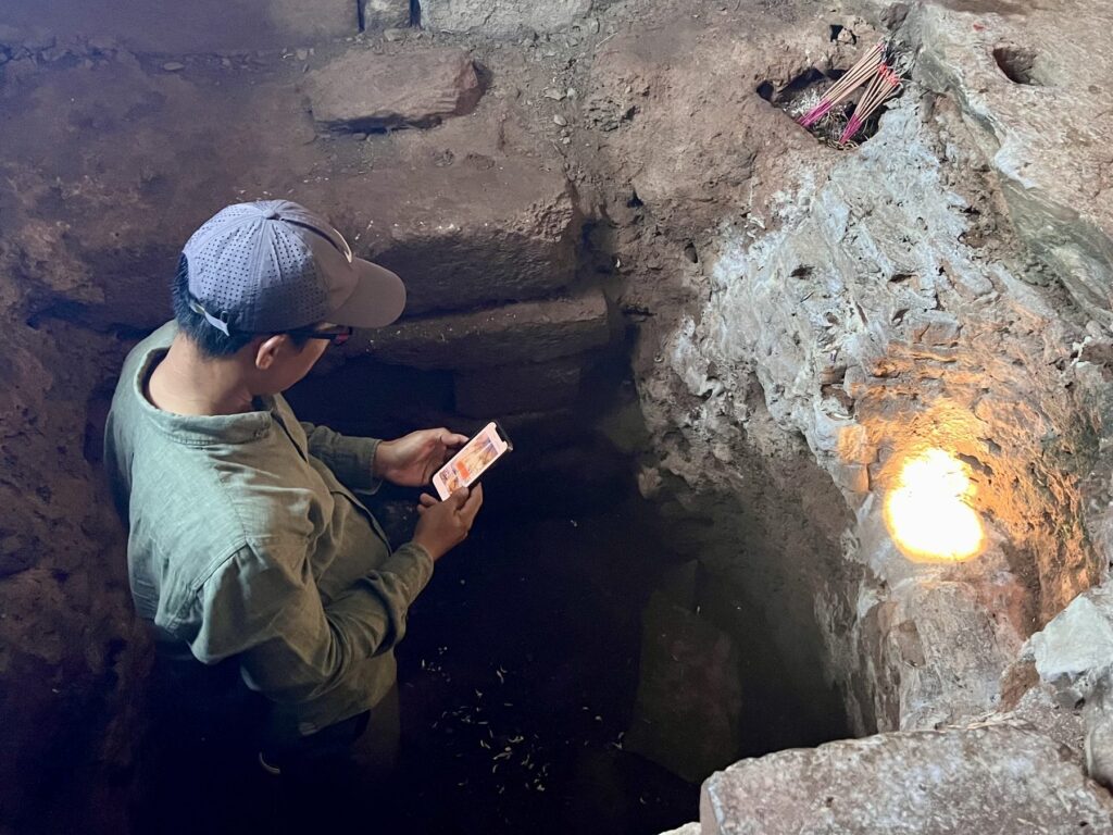 Guide Kanha Phum checking his phone in the pit of the Bakong central sanctuary as the zenith beam lands beside him
