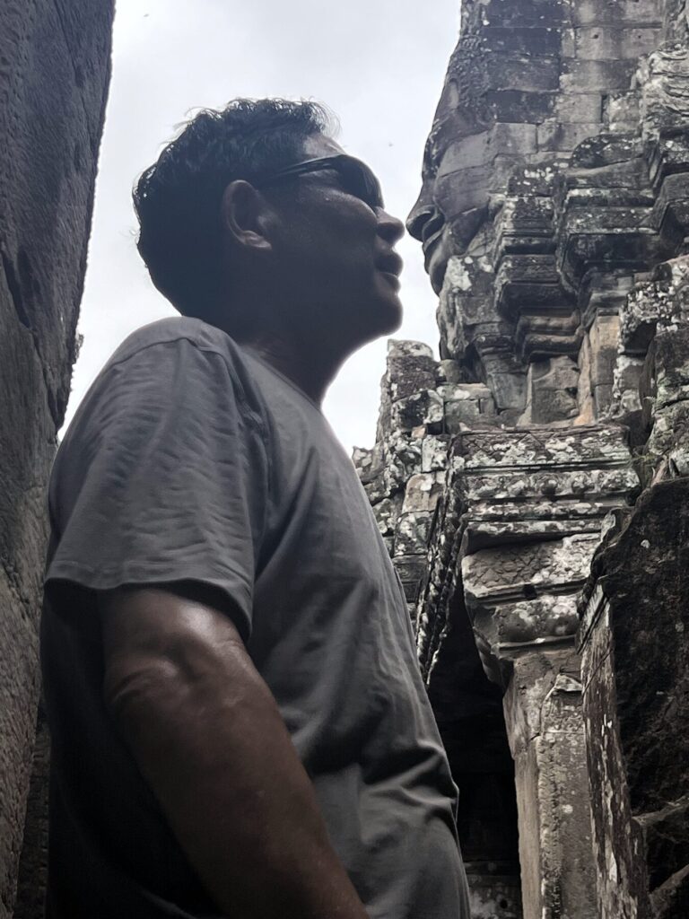The author in profile beside a carved stone face at the Bayon