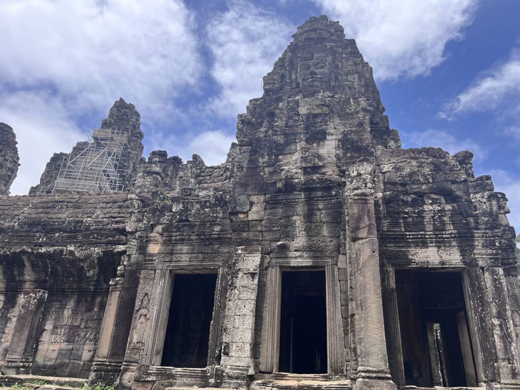The Bayon temple in Angkor Thom, with its stone face towers rising against a blue sky