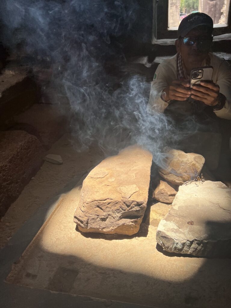Incense sticks left by earlier visitors smoking on a stone altar at the Bayon