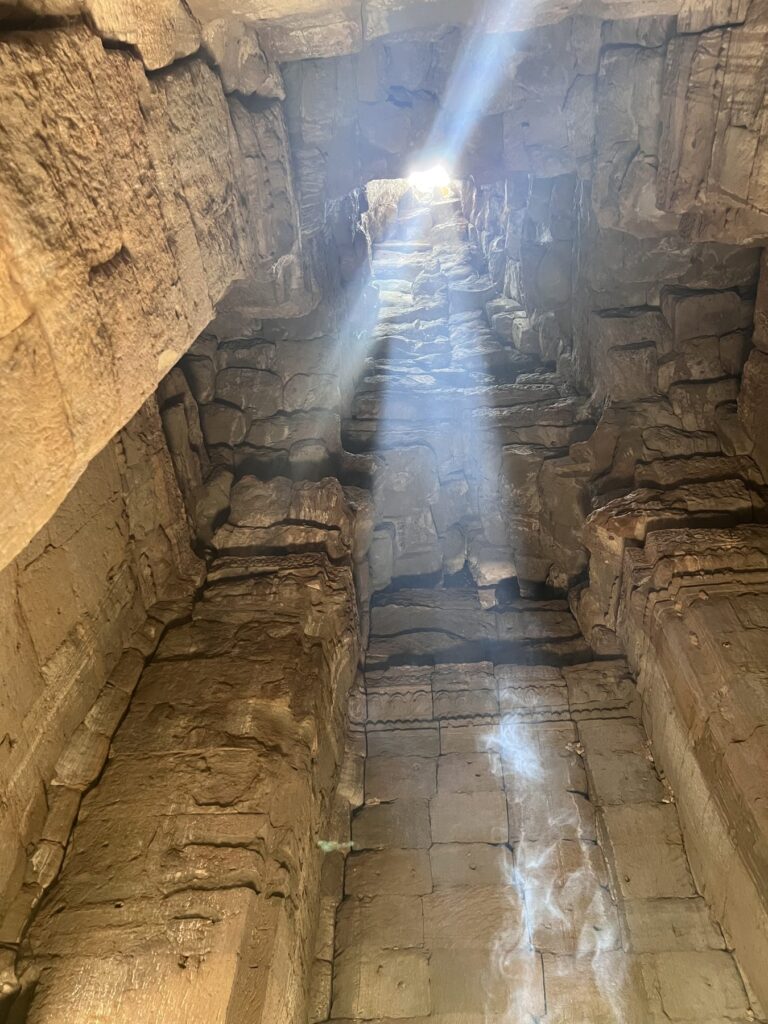 A zenith sunbeam shining into a stone chamber at the Bayon in April, with lens flare at the top