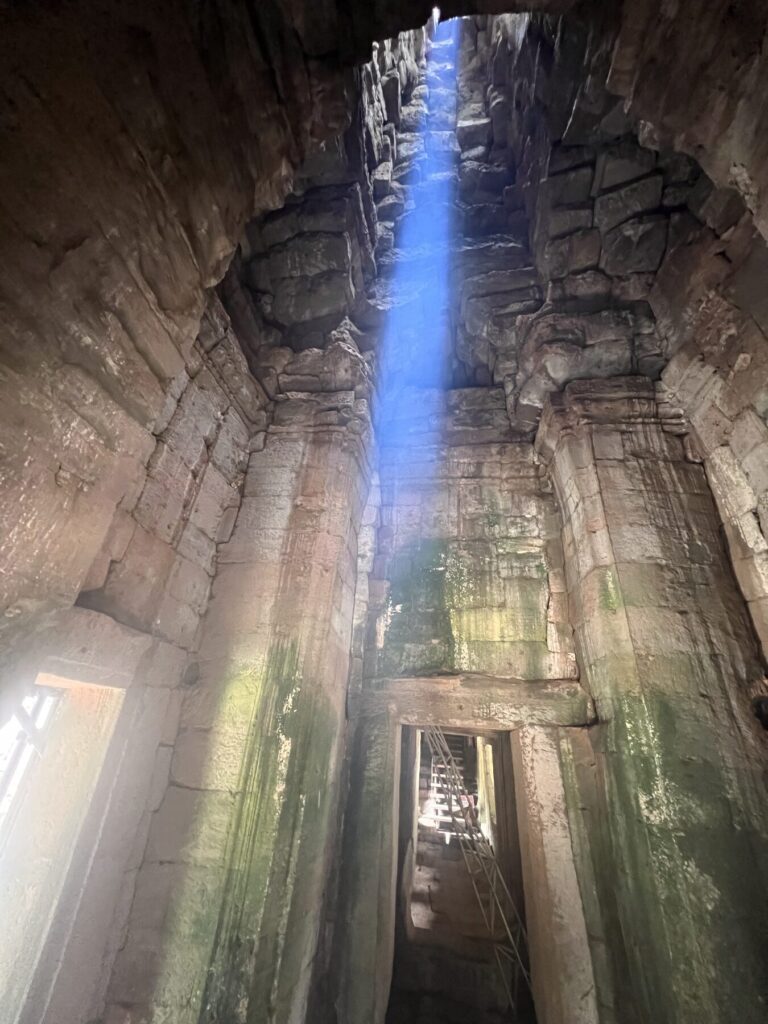 The zenith beam lighting the stone walls of a Bayon chamber in August