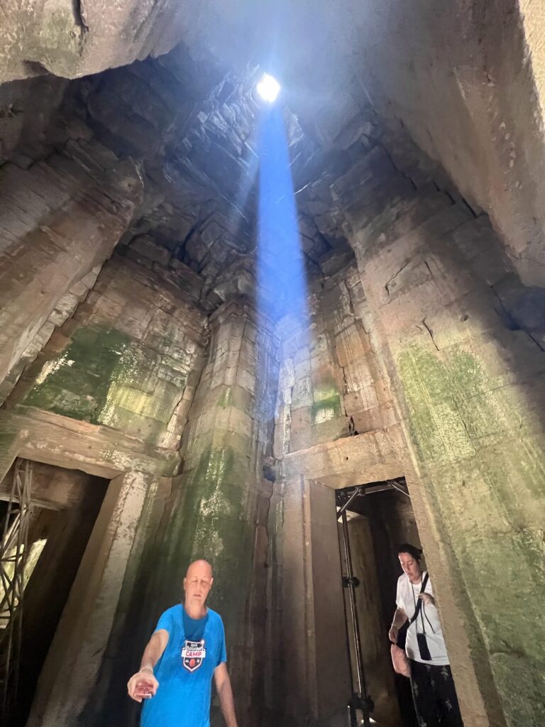 Visitors standing under the zenith sunbeam inside the Bayon