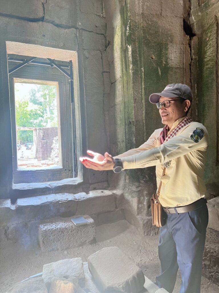 Guide Bon Chem holding out his hand toward the zenith light at the Bayon