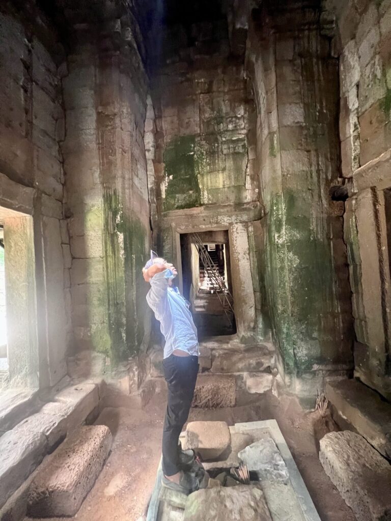Guide Kanha looking up at the zenith beam inside a Bayon chamber