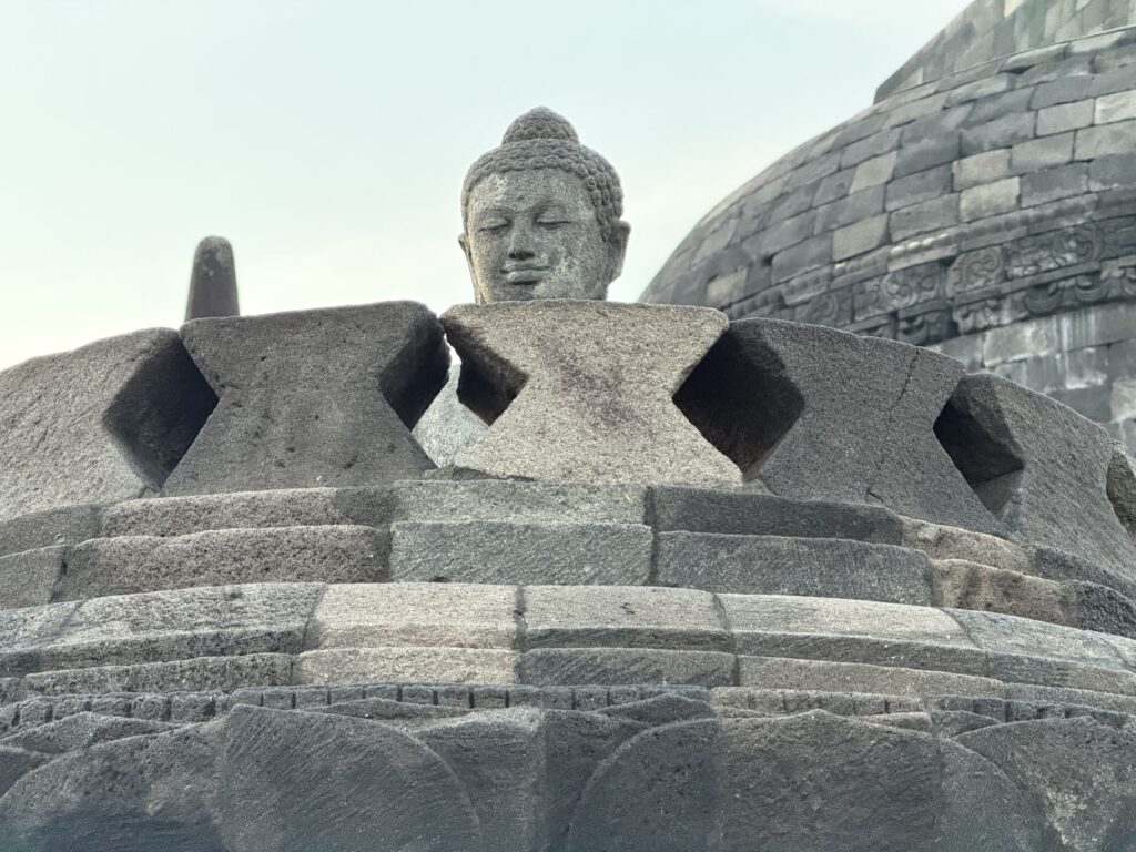 Seated stone Buddha inside an open stupa on the upper terrace of Borobudur