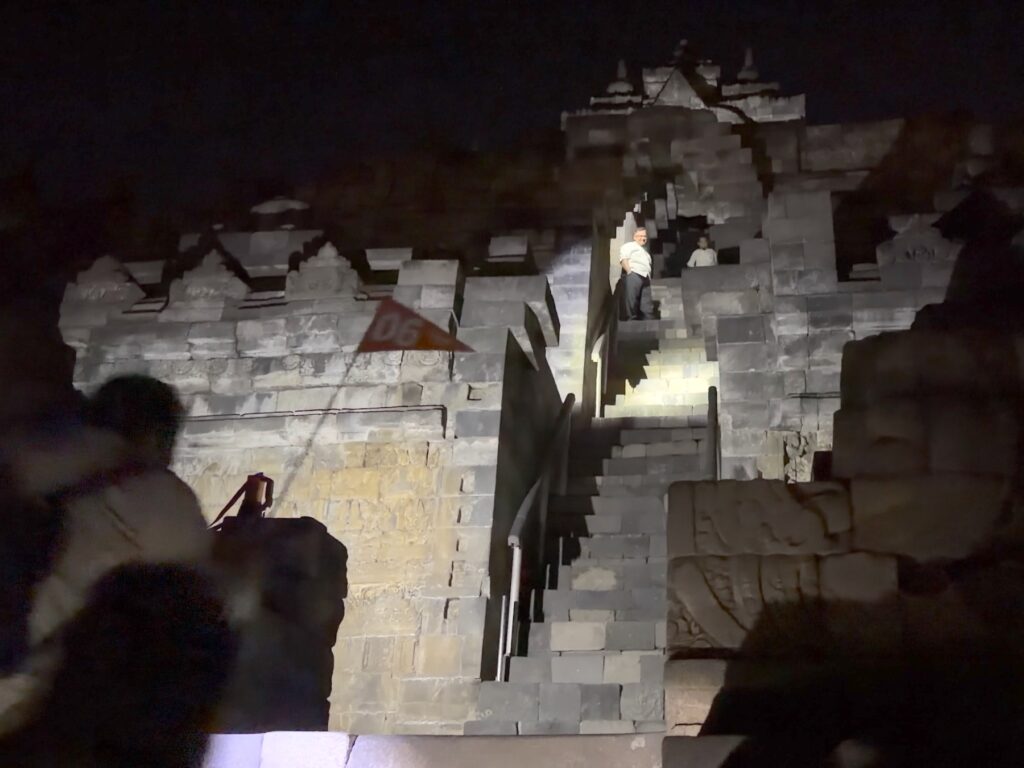 Flashlight beam on carved stone stairs during the pre-dawn climb at Borobudur