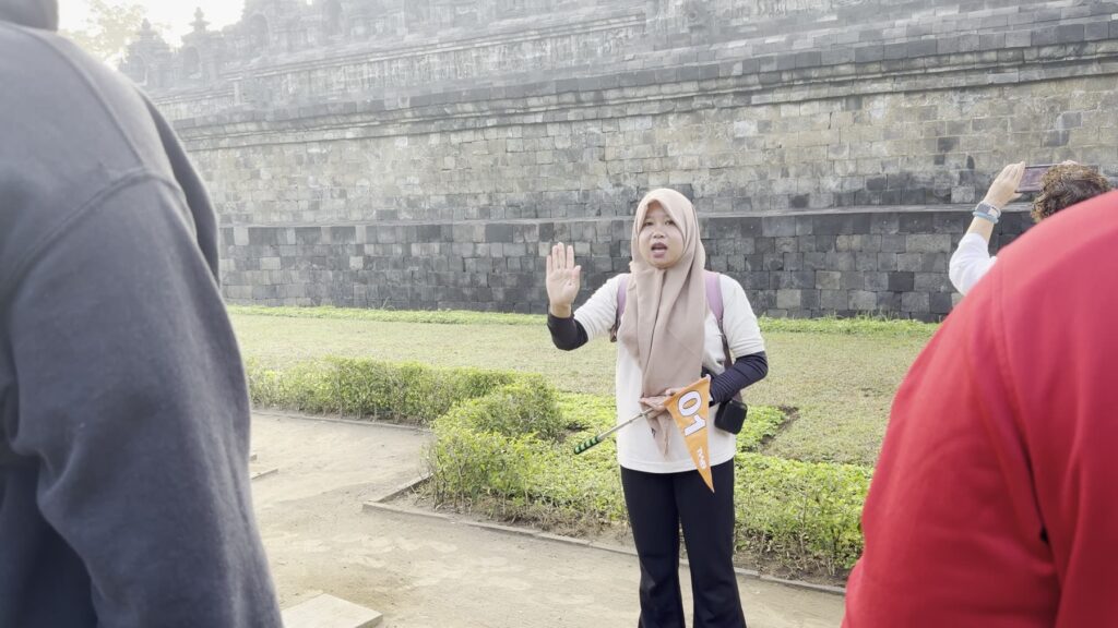 A guide explaining Borobudur’s history to a small group at the base of the monument