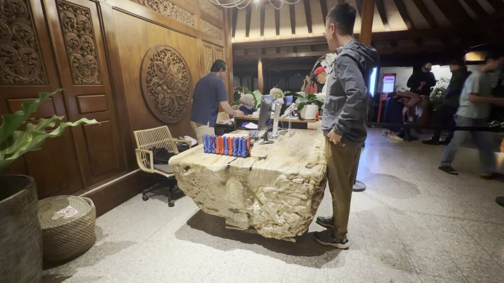 Visitors at a carved wooden check-in desk in the Manohara lobby before dawn