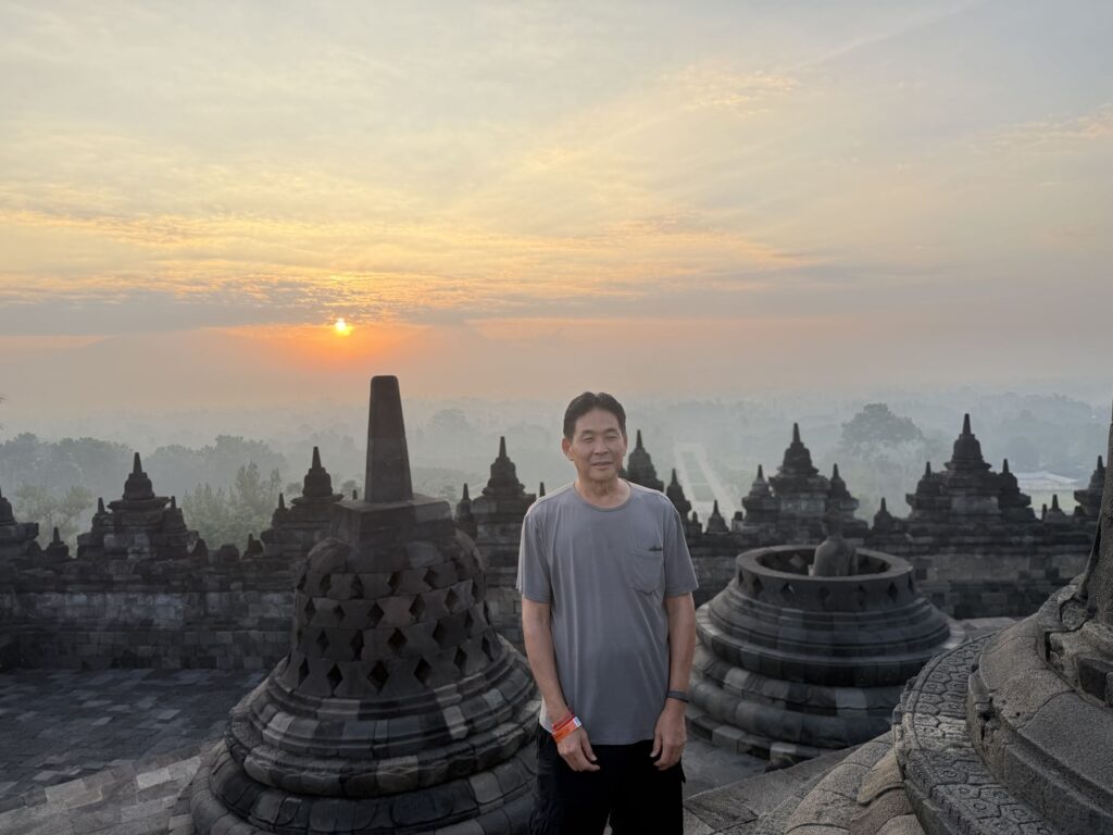 The author standing beside a latticed stupa as the sun rises at Borobudur