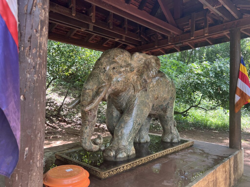 A stone elephant statue in a small wooden shrine near the Koh Ker pyramid