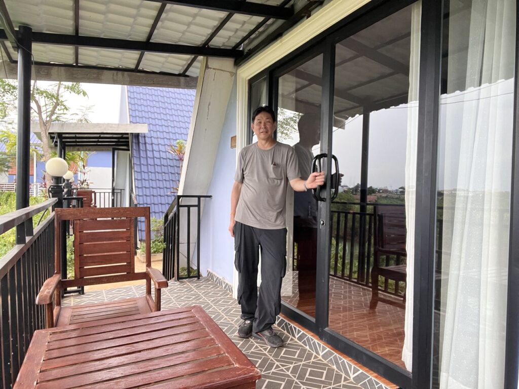 The author on the porch of an A-frame bungalow at the hotel near Koh Ker