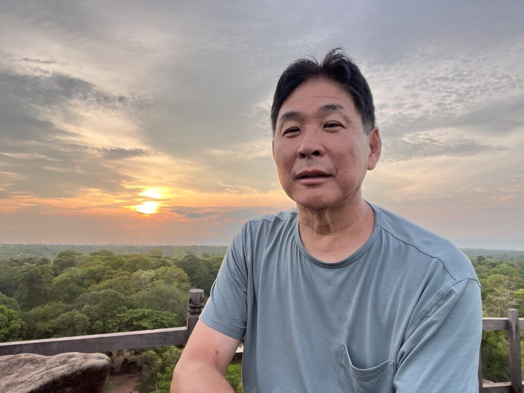 The author on top of the Koh Ker pyramid with the rising sun behind him
