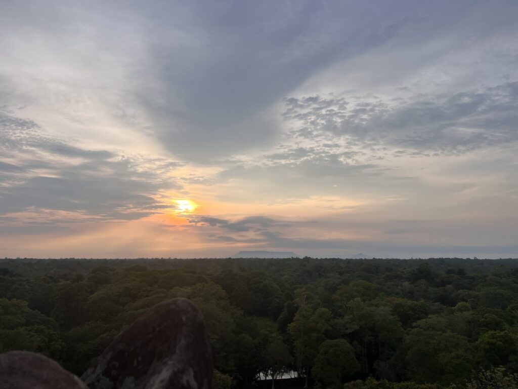 The sun rising through thin cloud over flat forest, seen from the top of the Koh Ker pyramid