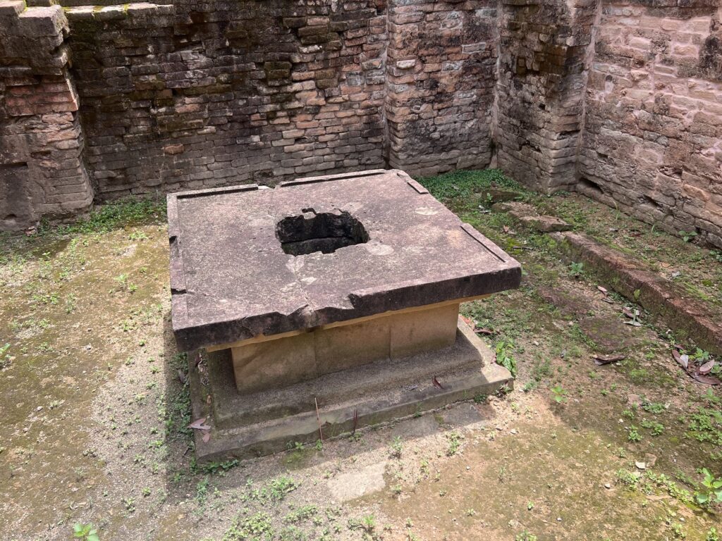 A stone pedestal inside a roofless brick sanctuary at Damrei Krap