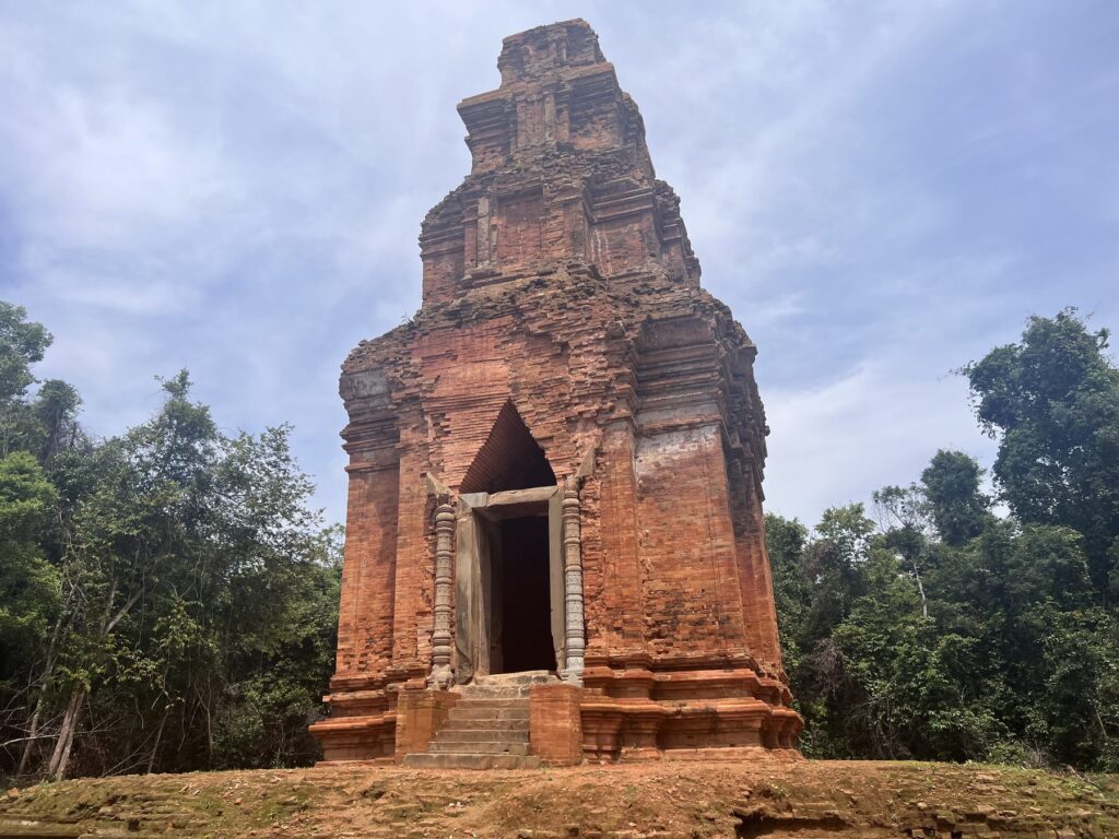Neak Ta temple, a single red-brick tower standing alone in a forest clearing on Phnom Kulen