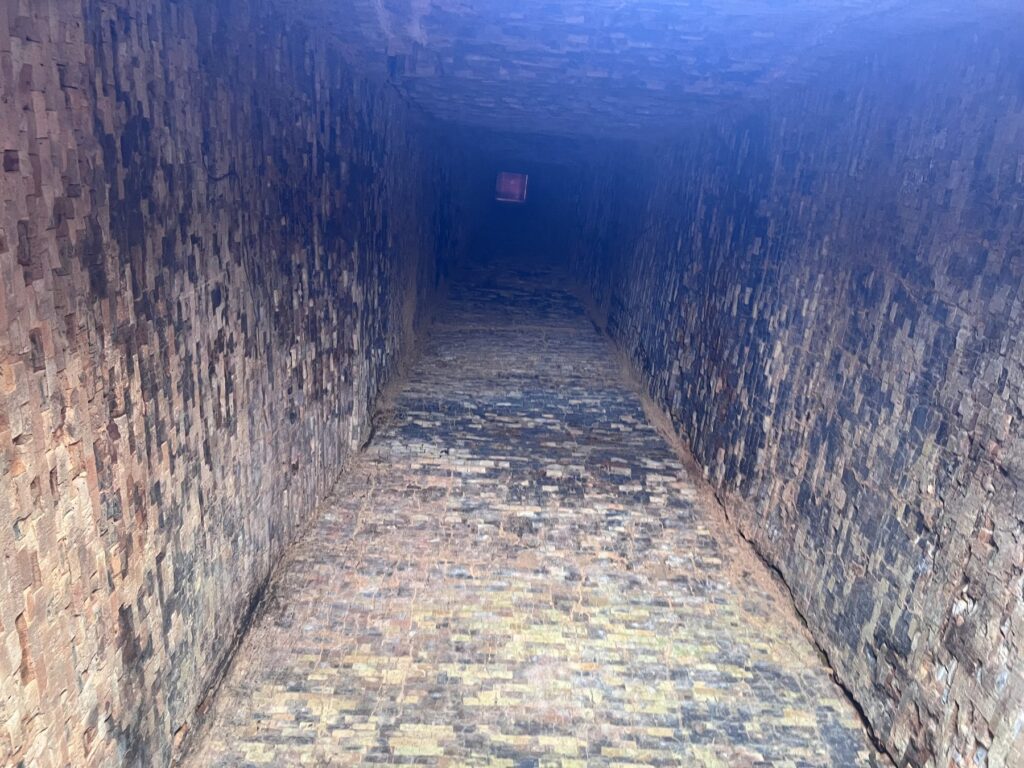 Looking up inside Neak Ta temple at soot-darkened brick walls and light from a gap in the roof