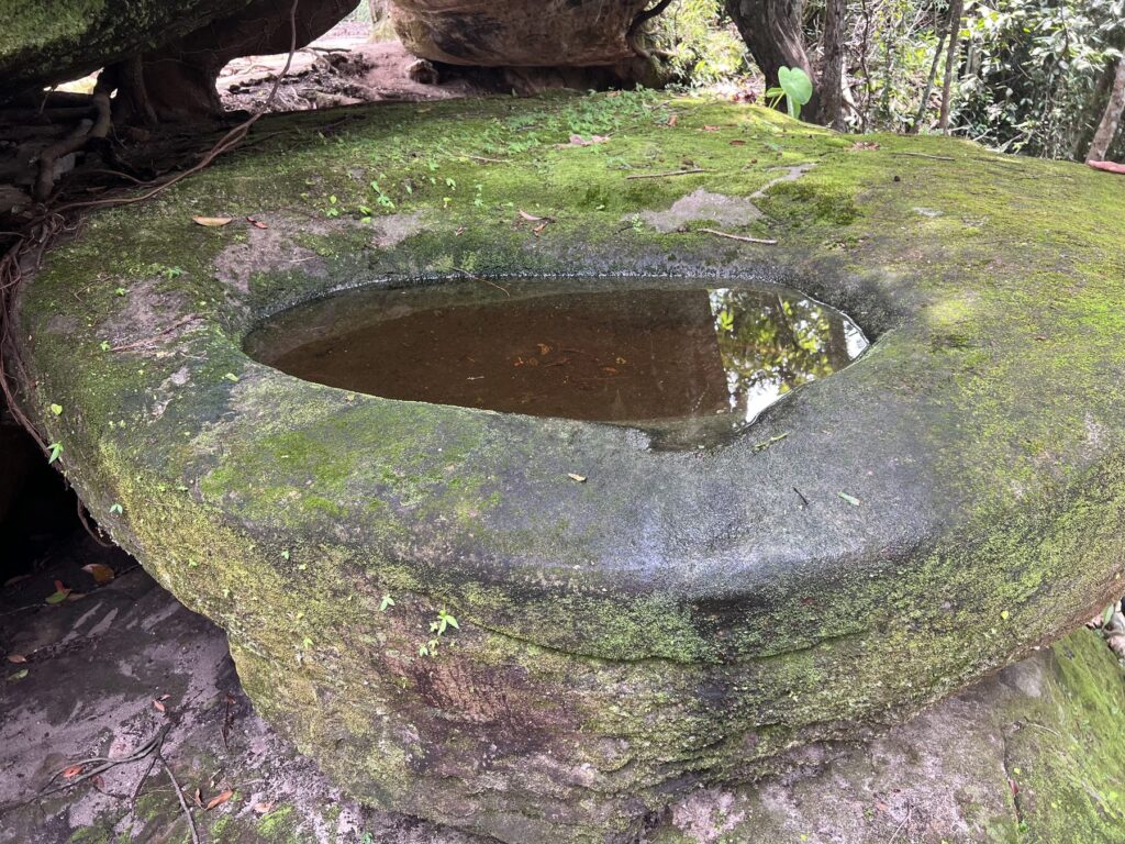 A large moss-covered stone basin filled with water at Peung Tbal on Phnom Kulen