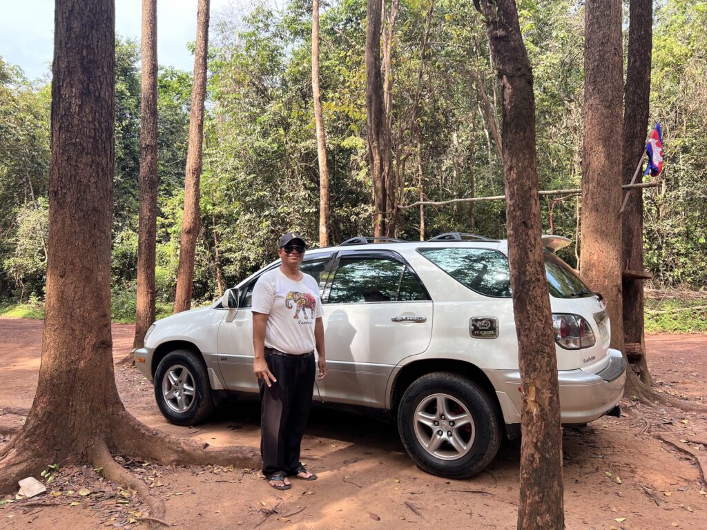 The private SUV and driver for the Kulen moto tour, parked under tall trees