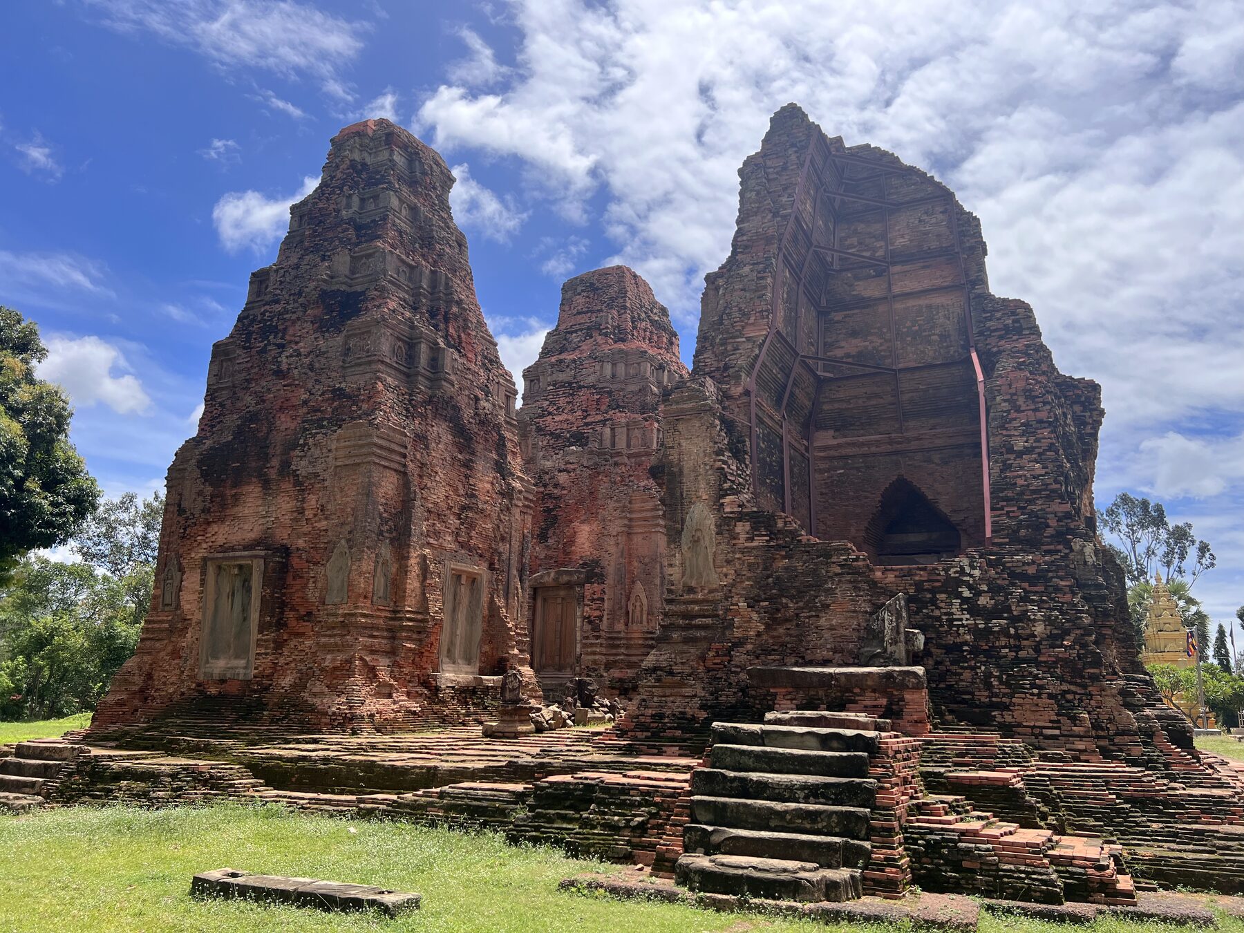 The brick towers of Lolei temple in the Roluos group under a blue sky with white clouds