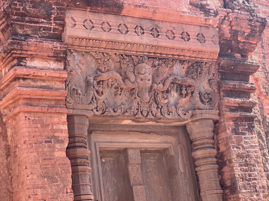 A carved sandstone lintel above a doorway on a brick tower at Lolei