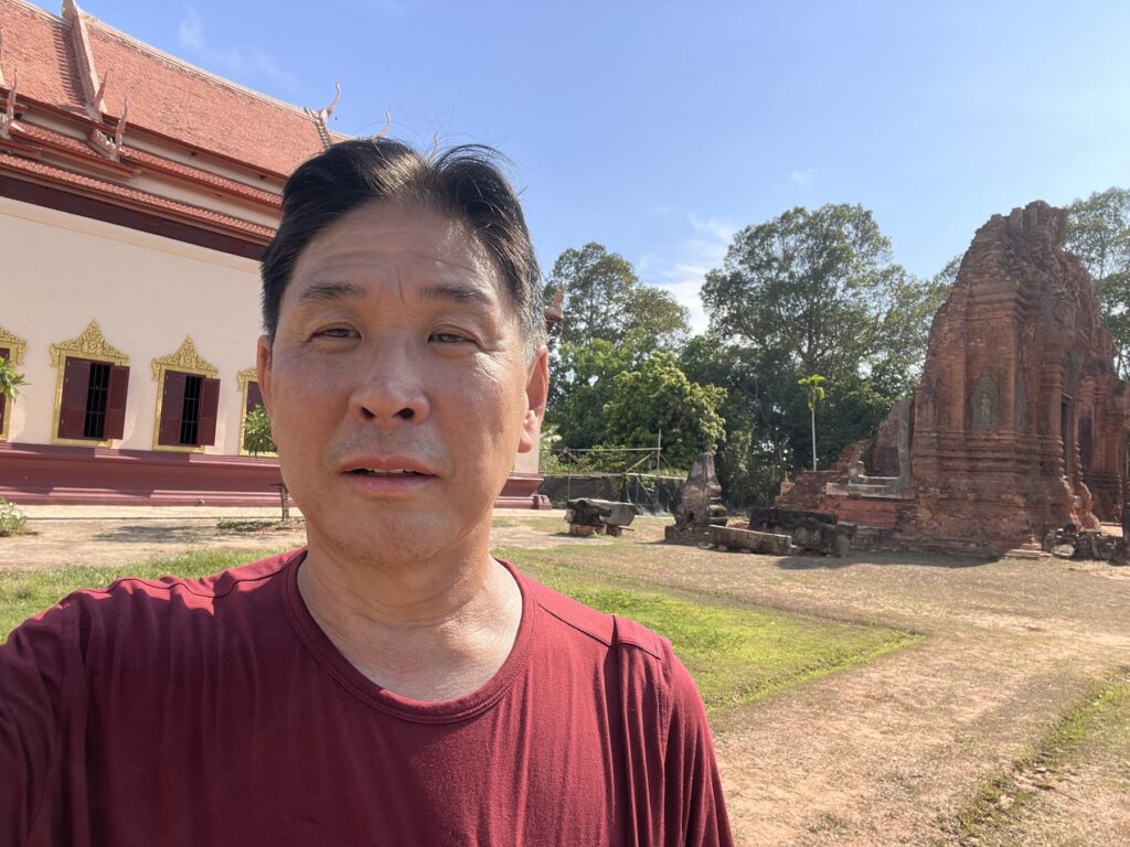 The author at Lolei temple in April 2025, with a brick tower behind him