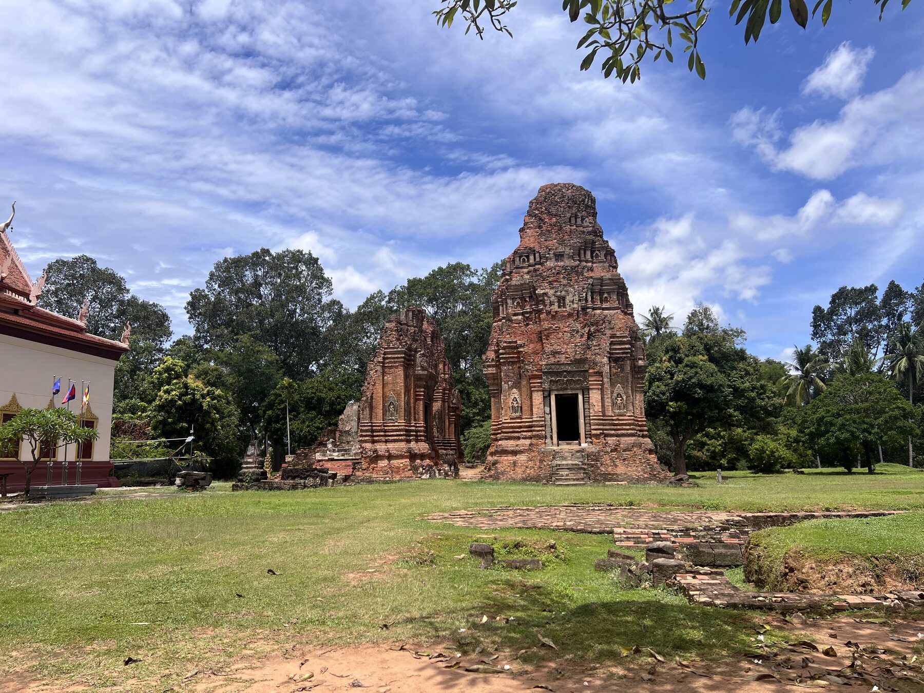 Lolei temple's brick towers seen across the grass, with a modern pagoda building at the left