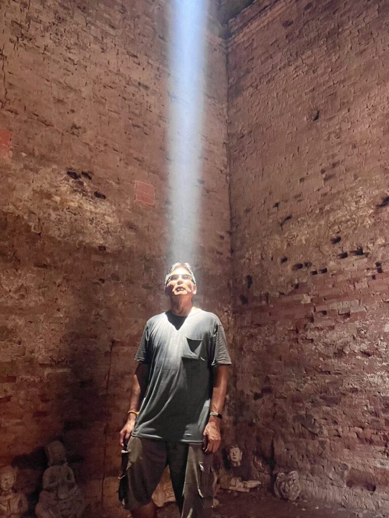 The author standing under the zenith sunbeam at Lolei, looking up at the opening