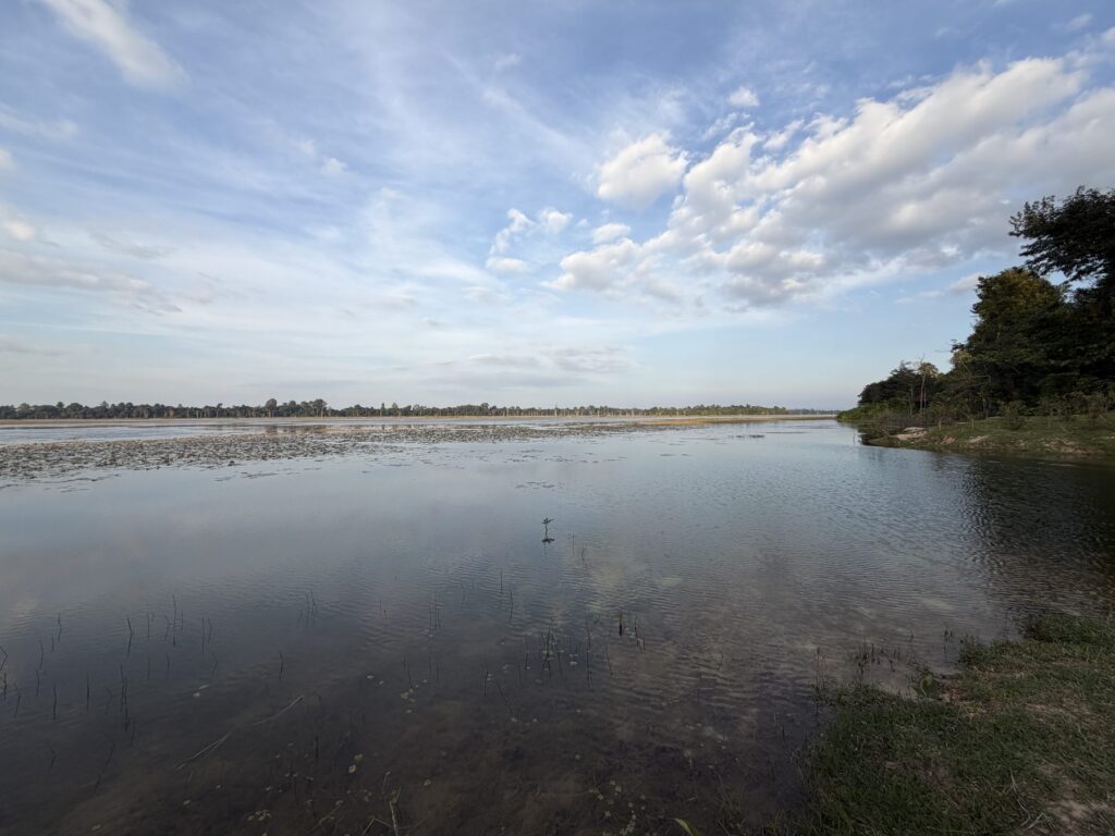 The still water of the North Baray reservoir at Angkor reflecting clouds in the afternoon