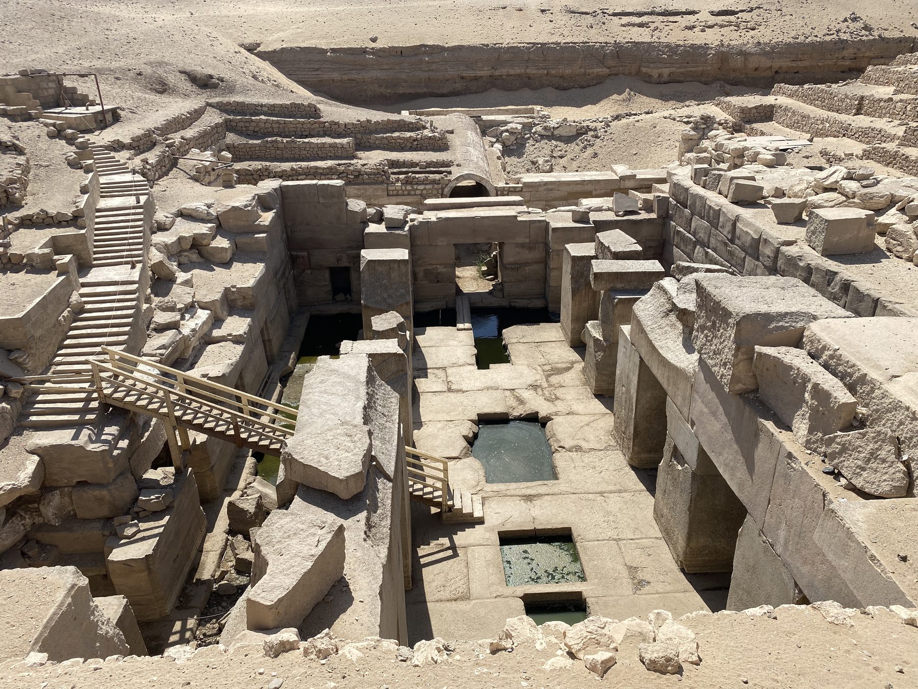 Looking down into the sunken Osirion at Abydos from the desert above, with megalithic walls and pools of water