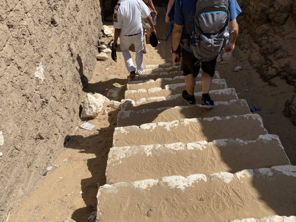 Tour group walking down sandy stone steps toward the Osirion entrance passage