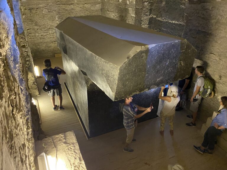 Tour group standing around a giant granite sarcophagus with its lid in the Serapeum of Saqqara