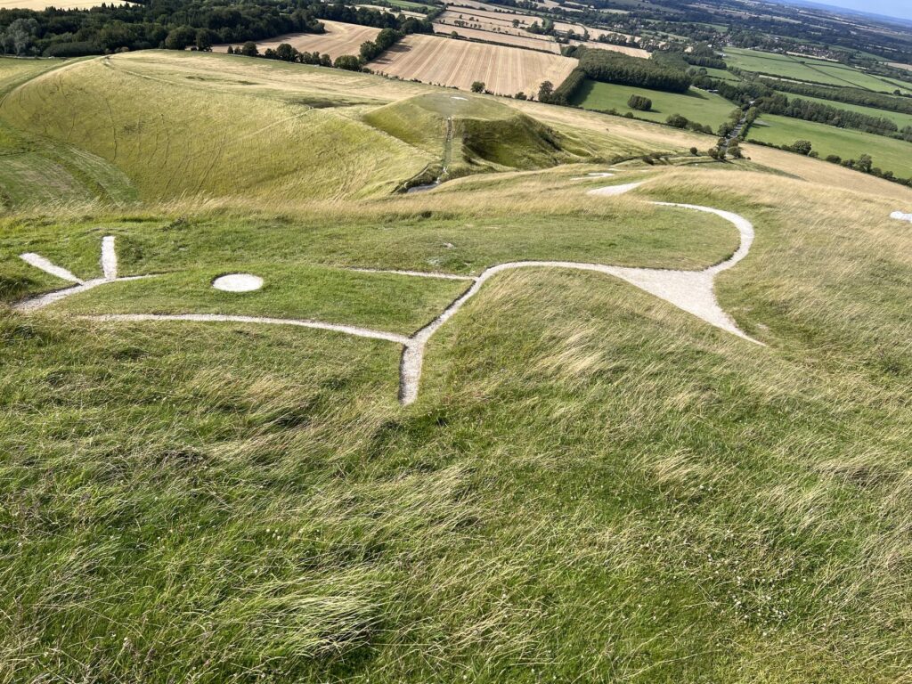 The Uffington White Horse chalk figure stretching across the green hillside in Oxfordshire